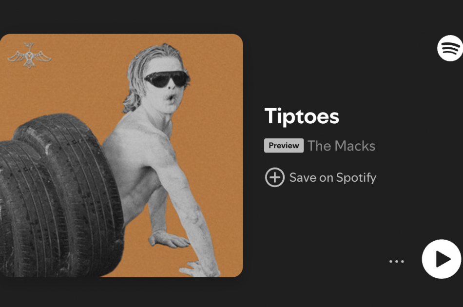 Picture of man painted white with sunglasses climbing out of a tire tunnel to promote The Macks new song "Tiptoes"